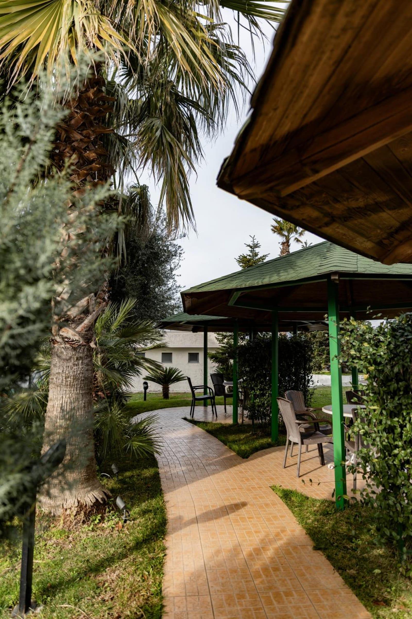 Tiled path between palms leading to the garden gazebos